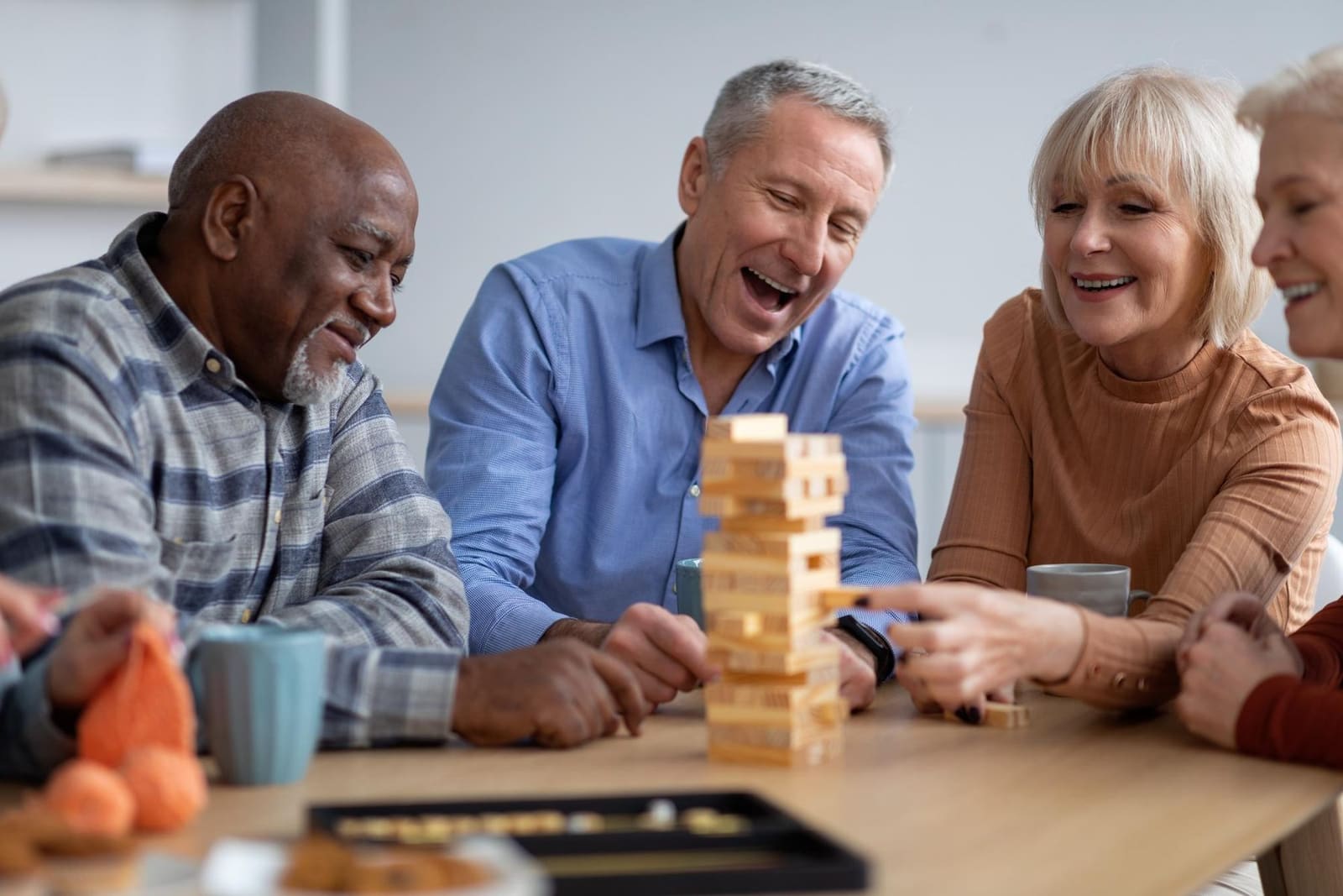 Friends laughing together over a game of tumbling towers at the table
